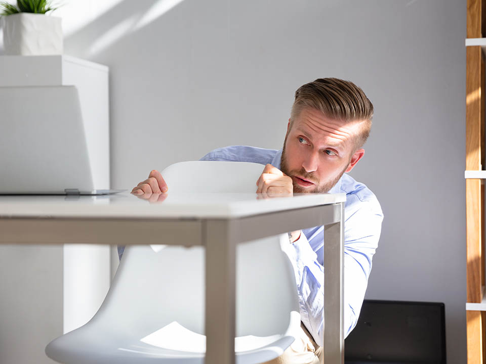 Afraid,Businessman,Peeking,From,The,Edge,Of,Desk,